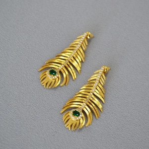Detailed view of vintage peacock feather earrings with green emerald and gold finish