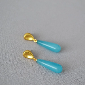Detailed macro of vintage brass earrings with water-drop shaped blue gemstones