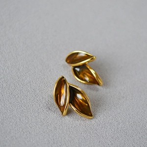 Artistic vintage gold-plated leaf earrings with amber enamel inlay on grey texture
