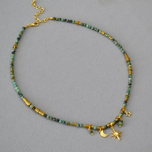 Bohemian turquoise beaded necklace with gold moon and star pendants on a grey background