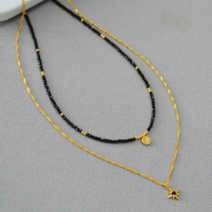 Close-up of double-layer gold chain with black spinel beads and star pendants
