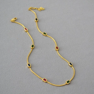Detail of gold chain necklace with colorful rectangular gemstones and lobster clasp closure