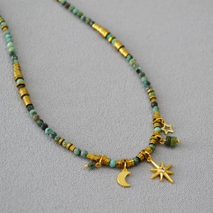 Detail of bohemian turquoise beaded necklace with gold moon and star-shaped pendants