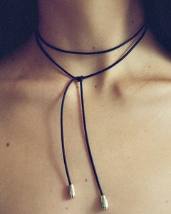 Detail of minimalist black cord choker with elegant silver water-drop pendants on model