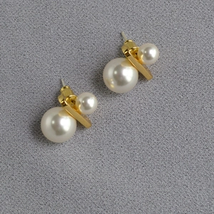 Detail of gold-plated brass earrings featuring large and small faux pearls on silver studs