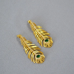 Detailed shot of peacock feather drop earrings with emerald green stones and diamond accents