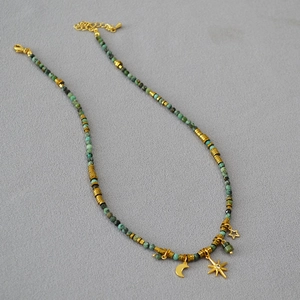 Detail of bohemian turquoise beaded necklace with gold moon and star charms and extension chain