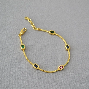 Detail of gold brass chain featuring colorful rectangular gemstones and lobster clasp