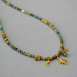 Macro detail of bohemian beaded necklace with gold sun, moon, and star charms