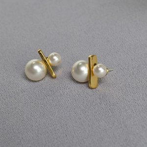 Detail of elegant gold plated brass studs featuring dual pearls and minimalist metal bar