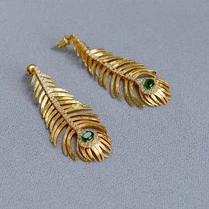 Detail of vintage peacock feather earrings with gold plating and green emerald stones