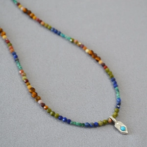 Détail du collier de perles en pierres précieuses avec pendentif soleil et turquoise