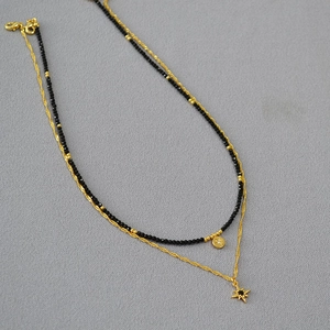 Detail of double-layer necklace with black spinel beads and golden star pendants