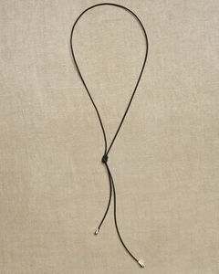 Detail of adjustable black cord necklace with silver teardrop pendants on linen