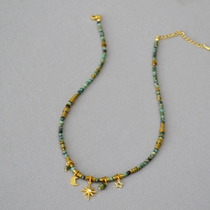 Close-up of turquoise beaded necklace with gold moon and star charms and extension chain