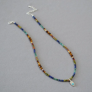 Détail d'un collier de perles multicolores avec pendentif argenté et pierre turquoise