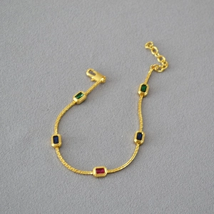 Macro view of gold-plated brass chain with colorful rectangular gems and lobster clasp