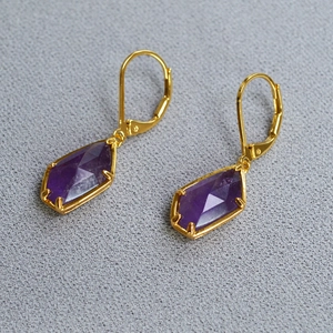 Macro shot of geometric purple amethyst earrings with gold lever-back hooks in a kite shape