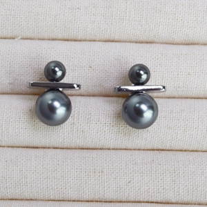 Detailed macro view of dark grey double pearl stud earrings on a velvet tray