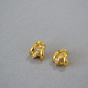 Vue détaillée des boucles d'oreilles dorées à couches incurvées serties de zircons