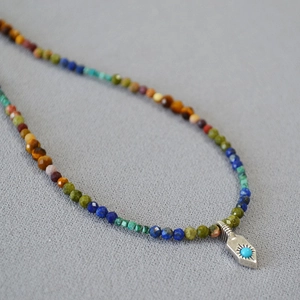 Gros plan du collier de perles en pierres naturelles avec pendentif turquoise et métal