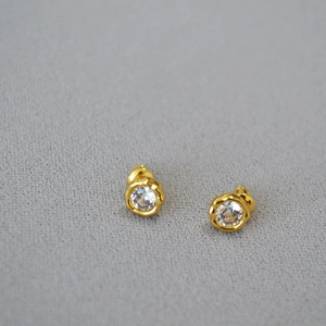 Macro detail of wave-edge stud earrings featuring sparkling round-cut cubic zirconia