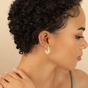 Bohemian gold sunburst earrings and minimalist jewelry set worn by a model