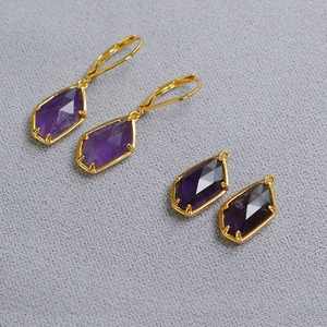 Macro detail of irregular faceted purple amethyst earrings with golden metal frames