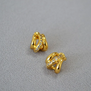 Boucles d'oreilles courbées plaquées or avec oxydes de zirconium sur tissu gris