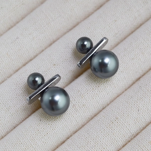 Macro detail of gray double pearl earrings with silver bar on ribbed jewelry tray