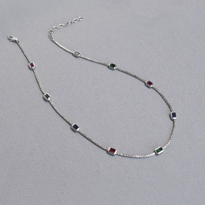 Detailed macro view of silver brass chain with rectangular red, green, and blue gemstones