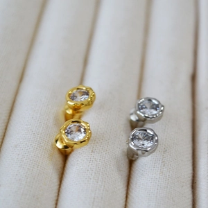 Close-up of minimalist bezel-set gold and silver cubic zirconia studs in jewelry box