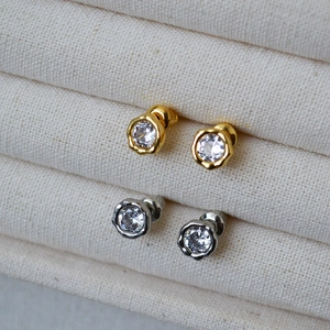 Macro view of dainty bezel-set zircon stud earrings in silver and gold plating