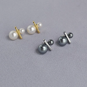 Detailed view of two pairs of gold and silver plated bar earrings with white and black pearls
