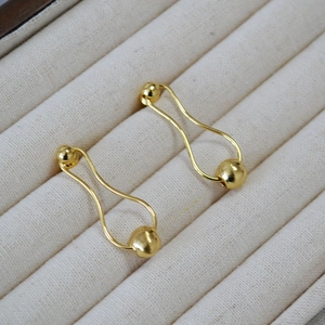 Macro detail of elegant pear-shaped gold-plated brass earrings with polished beads