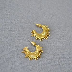 Detailed view of golden semi-circle sunburst earrings with hammered metal texture