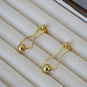 Close-up of golden geometric earrings with polished and brushed spheres on velvet