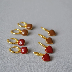 Détail de boucles d'oreilles rétro en émail rouge et marron avec cœurs et carrés dorés