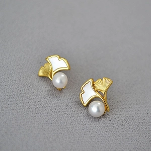 Ginkgo leaf earrings in gold-plated brass with freshwater pearls on a neutral background