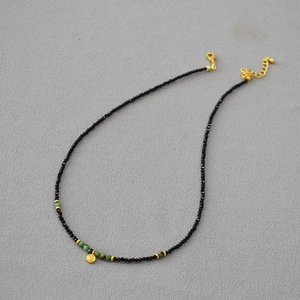 Detail der Perlenkette mit schwarzem Spinell, Türkis-Akzenten und goldenem Herzanhänger