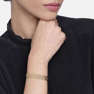Detail of a gold chunky chain bracelet with three rows of interlocking brick links