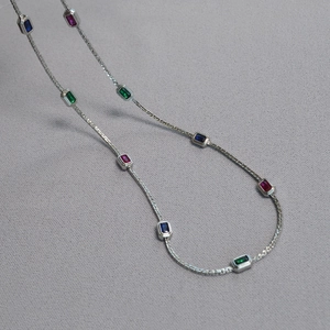 Detailed shot of silver brass chain featuring rectangular emerald, blue and pink gems