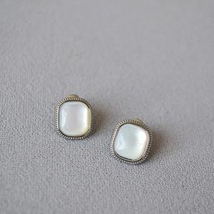 Macro shot of silver square stud earrings with white mother-of-pearl inlay and beaded edges