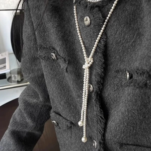 Élégant collier long en perles blanches de style Y porté sur un pull en laine gris