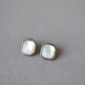 Detail of square mother-of-pearl stud earrings with silver milgrain decorative edges