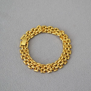 Detailed macro view of the gold-plated woven chain bracelet with a buckle clasp closure
