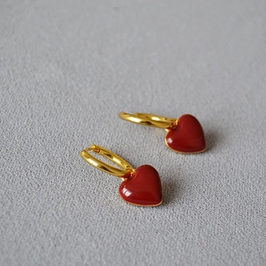 Détail de boucles d'oreilles cœur vintage en émail rouge foncé et métal doré