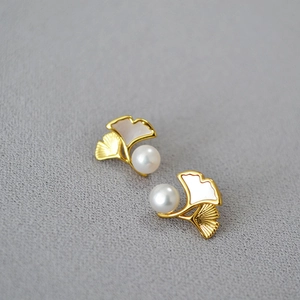 Macro shot of ginkgo leaf earrings with 18k gold plating and round white pearls