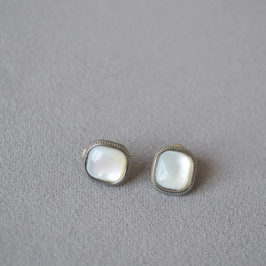 Macro shot of silver square earrings with iridescent mother of pearl and milgrain edges
