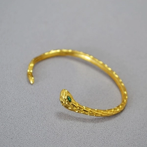 Bracciale a serpente placcato oro minimalista con occhi in gemma verde e trama a squame